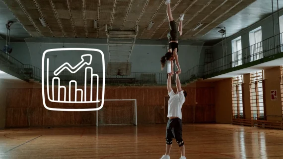 Deux cheerleader effectuant un partner stunt dans un gymnase vide. Une illustration de statistique apparait en blanc sur la gauche